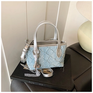 Close-up of light blue denim bucket bag with silver handle and diamond texture