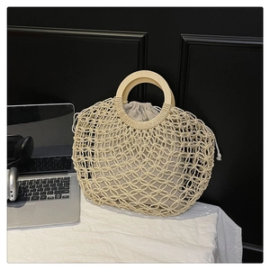 Detail of hollow woven tote bag featuring round wooden handles and drawstring cotton liner