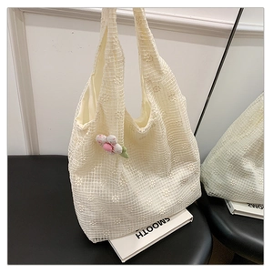 Detail of cream mesh tote bag with delicate flower embroidery and pink floral charm