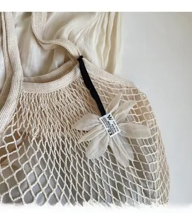 Close-up of cream woven mesh tote bag with textile flower charm and detailed stitching