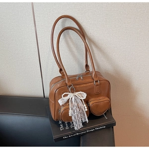 Detail of glossy brown handbag with heart pocket and pearl lace bow on a book
