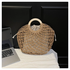 Detail of hollow woven straw tote bag featuring round wooden handles and cotton inner bag