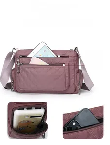 Detail view of purple nylon quilted bag showing multiple front zipper pockets and side pouch
