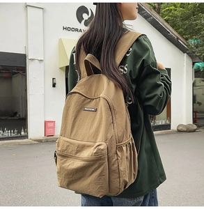 Detailed back view of khaki nylon backpack featuring MACHUGE leather logo and front pocket