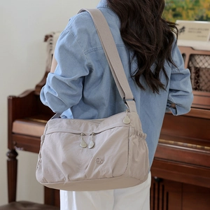 Detail of light beige nylon crossbody bag with multi-zipper pockets and pleated side pouch