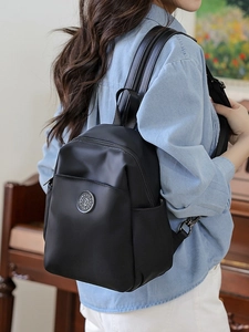 Minimalist black nylon backpack for women with metallic logo in a stylish home setting