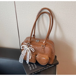Detail view of brown faux leather Boston bag with heart pocket and pearl bow pendant