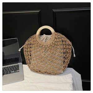 Detail of hollow woven straw handbag with wooden handle and drawstring fabric lining
