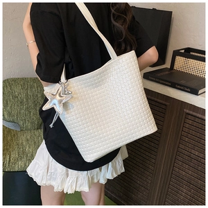 Detail of white woven bucket bag with silver star charm and slim shoulder strap