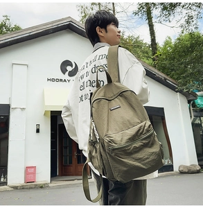 Detail shot of the olive green canvas backpack showing the spacious side pockets and durable straps