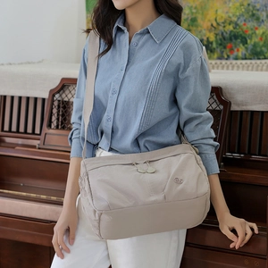 Detail of light beige casual crossbody bag with dual zipper pockets and a wide strap