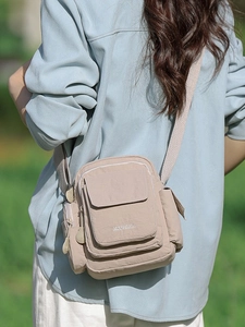Crossbody nylon bag in light beige with multiple pockets and adjustable strap shown on model
