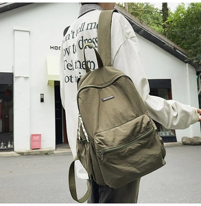 Side view of olive green nylon backpack showing side pocket and durable fabric texture