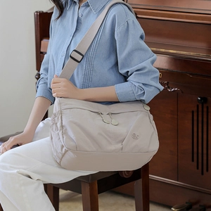 Detail of adjustable strap and multi-pocket design on casual beige nylon tote bag