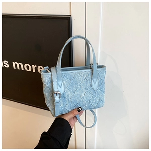 Detail of light blue pleated mini bucket bag with top handles and adjustable strap