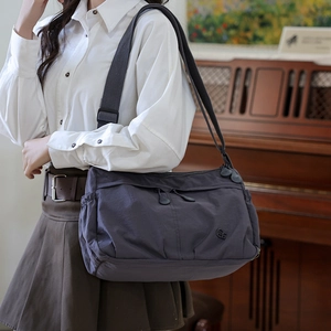 Detail of dark grey nylon pleated tote bag with multiple zippers and adjustable strap