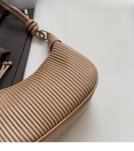Detail of soft pleated faux leather texture and knotted shoulder strap on beige bucket bag