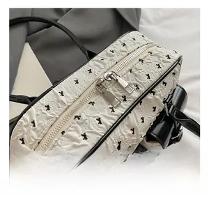 Detail of silver metal double zippers and black bow pattern on white bubble fabric bag