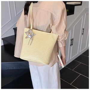 Detailed woven texture on large cream bucket bag with star charm and shoulder strap