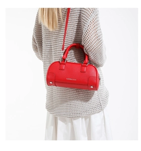 Sac bowling en cuir rouge à grain litchi avec logo argenté porté par un modèle