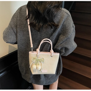 Detail of woven straw bucket bag with pink leather trim and pearl tulip charm
