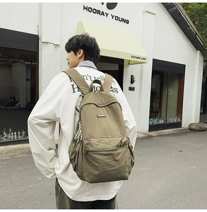 Detail view of the olive green canvas backpack side pocket and adjustable straps