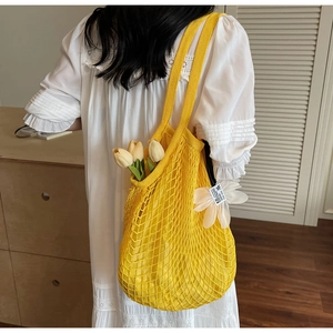 Detailed close-up of bright yellow knitted mesh tote bag with a white woven label on the side