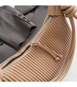 Detail of camel leather pleated handbag with silver zipper and knotted handle design