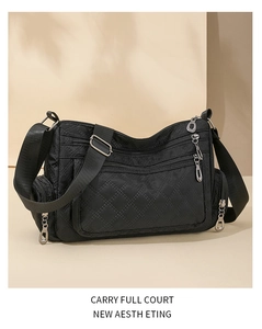 Detailed view of the black quilted nylon fabric and multiple zippers on this crossbody bag