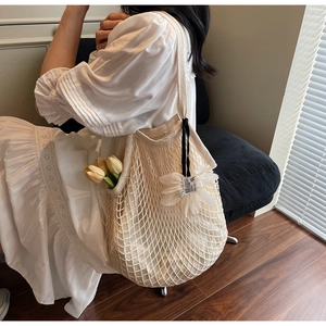 Macro detail of cream knit crochet tote bag with floral charm and summer beach vibe