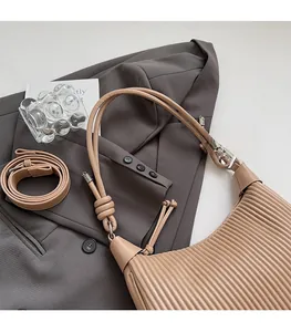 Detailed view of the pleated texture and adjustable strap on the beige shoulder bag