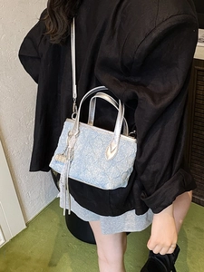 Chic light blue textured bucket bag with silver handles and decorative fringe tassel
