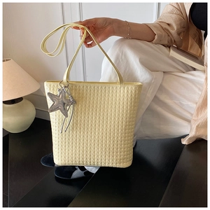 Close-up of woven texture tote bag with a sparkling silver star pendant charm