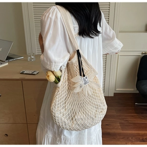 Close-up of beige mesh knit tote bag featuring a delicate 3D white fabric flower pendant