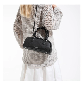 Mannequin portant un sac cylindre en cuir noir avec logo blanc et détails argentés