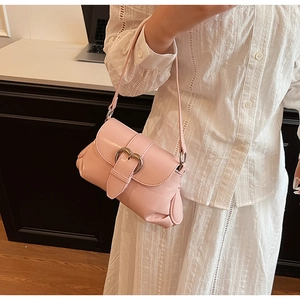 Detailed shot of pink leather saddle bag with silver heart buckle on elegant lace dress