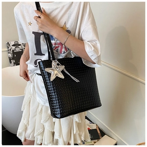 Detail of black woven texture tote bag with silver star charm and fringe tassels