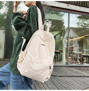 Outdoor view of a beige nylon backpack featuring minimalist design and large capacity