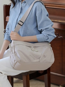 Large capacity beige nylon crossbody bag with pleated details and wide shoulder strap