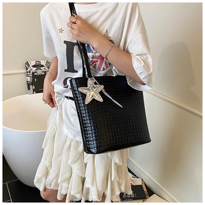 Detail of black crocodile pattern bucket bag featuring a silver star pendant and long tassels
