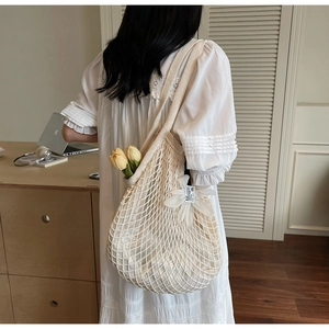 Detail of hand-woven mesh tote bag with 3D white floral decor shown on model shoulder