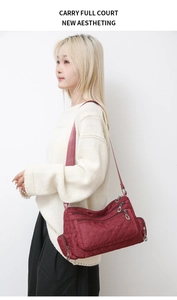 Close-up of lightweight burgundy quilted nylon crossbody bag with multiple zippers