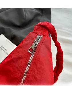 Close-up of red pleated crossbody bag featuring smooth silver metal zipper and nylon texture