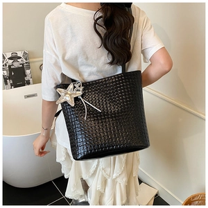 Detail of black woven texture tote bag featuring a decorative silver starfish charm
