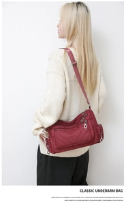 Detailed macro view of burgundy quilted nylon shoulder bag showing zipper compartments