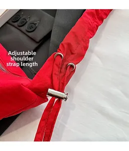 Detail of adjustable red shoulder straps with silver metal toggles on a slouchy bag