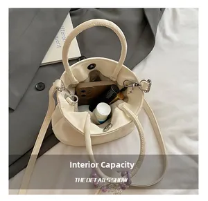 Top view of cream pleated bucket bag showing interior space with phone and lipstick