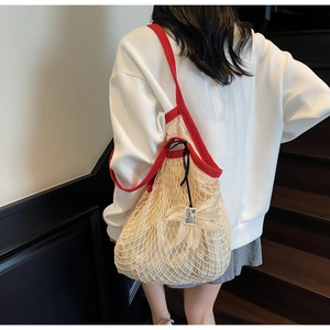 Detail of red knit strap and cream woven mesh bag with drawstring fabric lining