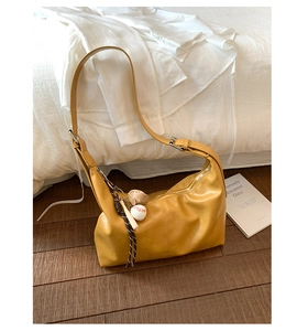 Close-up of bright yellow large capacity hobo bag with baseball charm on wooden floor