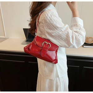 Detail of red patent leather saddle bag with silver heart buckle on a model shoulder